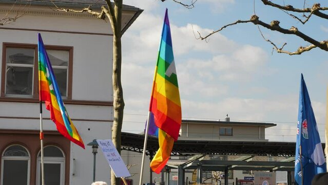 Rainbow flags blowing in the wind at a peace demonstration. The word pace is painted on the flags. Anti war. Slow motion.
