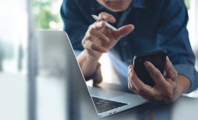 Businessman making face time video calling, using online meeting app via mobile app on smart phone with laptop computer and digital tablet on office table