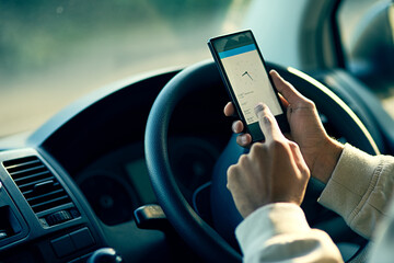 Staying on schedule. Closeup shot of an unidentifiable delivery man using a cellphone while sitting in his van.