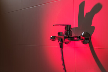 Fototapeta na wymiar Close up of chrome faucet in modern bathroom flooded with pink light. Bathroom planning design.