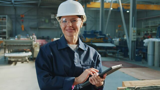 Portrait smiling man worker wearing hard hat and using digital tablet computer in the warehouse. Look around.