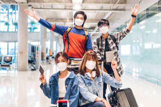 Young happy friend traveler in quarantine for coronavirus wearing surgical mask face protection hold passport and ticket before long travel vacation flight at International terminal airport