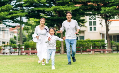 Naklejka na ściany i meble Portrait of enjoy happy love asian family father and mother run with cute little asian girl child smiling play and having fun moments good time in summer park at home