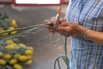 Women weaving fishing nets in seaport, tying and repair