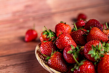 Ripe red strawberries in a basket on a wooden background