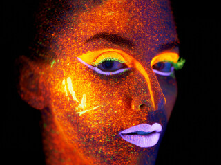 Ready for the nightlife. Portrait of a young woman with with neon paint on her face posing.