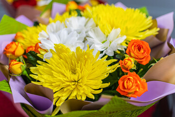 Obraz na płótnie Canvas Beautiful flower bouquet of yellow chrysanthemums and red-yellow roses. A beautiful gift for newlyweds.