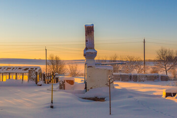 a Russian stove left over from a burnt-out wooden house stands alone in the middle of a snow-covered field