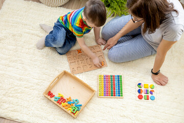 Montessori material. Colored movable alphabet made of wood on a blackboard. Baby boy.