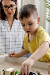 Montessori material. Little boy with his mom explores the farm animals in the game.