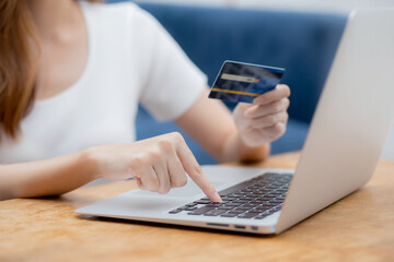 Hand of young woman holding credit card buying shopping online with laptop computer, girl purchase and payment on internet, commerce and e-business, transaction for finance, business concept.