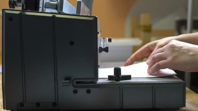 faceless worker using binding machine in printing office