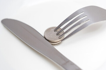 Inflation in Russia. A Russian ruble coin on a white plate, a fork and a table knife next to it