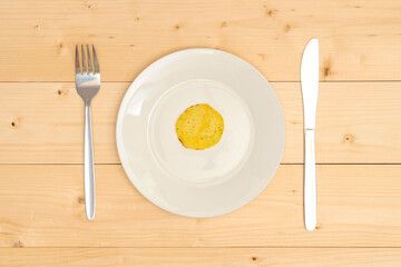 One crispy potato chip on a white plate top view