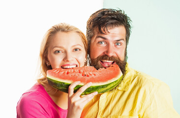 Happy face closeup of couple enjoying watermelon. Cheerful couple holding slices of watermelon. Funny face.