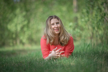 Beautiful blonde young woman in a pink blouse in the park.