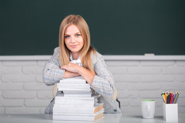 Female student on lesson lecture in classroom at high school or college. Cute student girl with books on blackboard background with copy space.