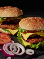 homemade hamburger with French fries tomatoes and cheese and herbs and onions