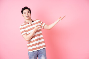 Young Asian man posing on pink background