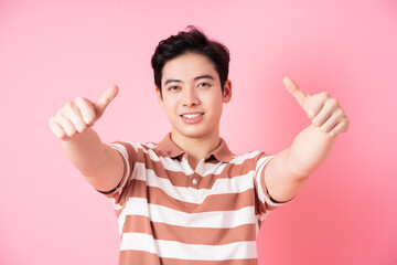Young Asian man posing on pink background