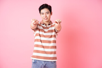 Young Asian man posing on pink background