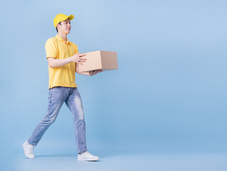 Full length image of Asian delivery man on blue background