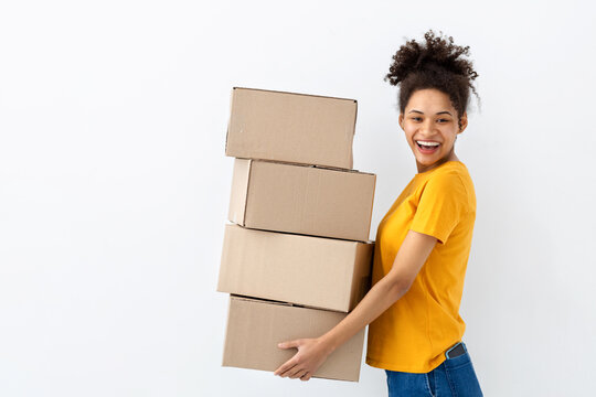 Young happy African American woman with stack of cardboard boxes on white background. Copy spa