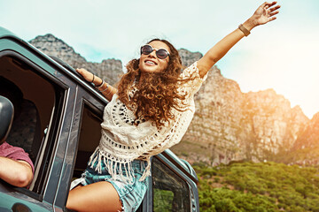 Bring on the good times. Cropped shot of a young woman leaning out a car with her arms outstretched...