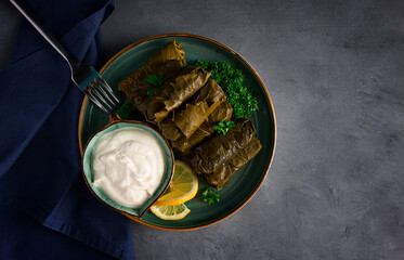 Dolma, cabbage rolls, grape leaves with filling, white sauce, lemon and herbs, rustic, selective focus, no people,