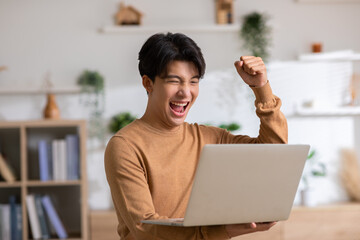 Asian man is smiling and expressing happy feeling on the computer laptop screen. young male got...