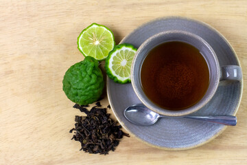 Bergamot tea or Earl Grey tea in ceramic cup and fresh bergamot fruit with sliced on brown wooden...