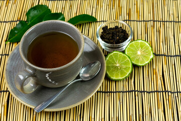 Bergamot tea or Earl Grey tea in ceramic cup and fresh bergamot fruit with sliced on mat.