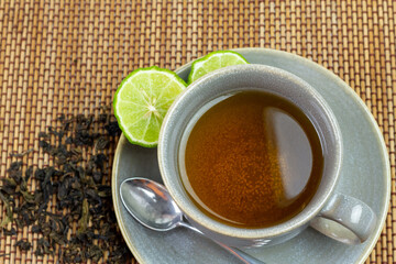 Bergamot tea or Earl Grey tea in ceramic cup and fresh bergamot fruit with sliced on mat, top view.