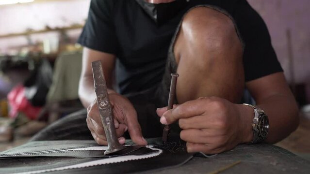 Shoe craftsmen are making brogue wingtip shoes made of leather which are done manually in a small home workshop