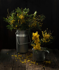 Still life with a bouquet of yellow spring flowers in a jug on a wooden background in the sunlight.