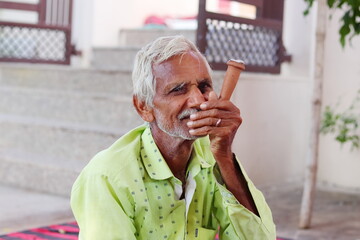 An Indian aged b man smoking a small hookah, Indian village traditional