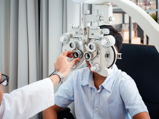 India cute boy sitting in an eyeglass shop with an optometrist specializing in eye disorders and primary eye health looking for a lens to suit his eyesight and get the most effective eyeglasses.