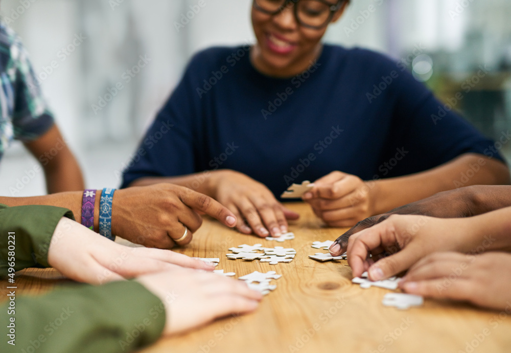 Poster building success together. shot of a group of people building a puzzle together.