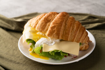 Croissant sandwich with poached egg, on breakfast plate