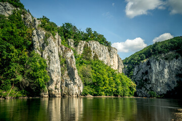 Fototapeta na wymiar Rocks of the Danube Gorge with green forest, blue sky, water and beach of the Danube. Danube Gorge in Bavaria Germany.