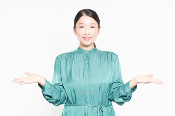 白い背景の前に立って案内のジェスチャーをする主婦