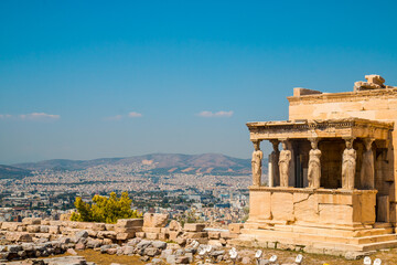 Obraz premium Panoramic view on Athens from Acropolis, Erechtheion or Temple of Athena Polias with caryatid, sculpted female statue serving as an architectural support the porch of the Maidens