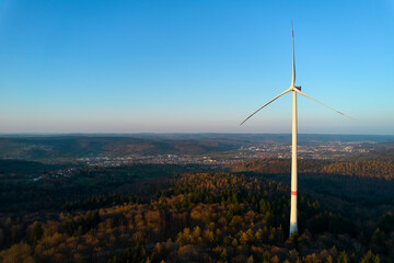 A wind turbine in the forest. Alternative energy to expensive gas and oil. Generator between trees...