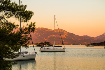 View on sailing yachts staying on anchor in the Russian bay, half island Poros, Greece with small...