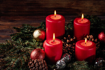 four burning Red advent candles in advent wreath decoration on wooden dark background. tradition in time before Christmas. xmas lights with christmas fir deco background concept. Festive still life.