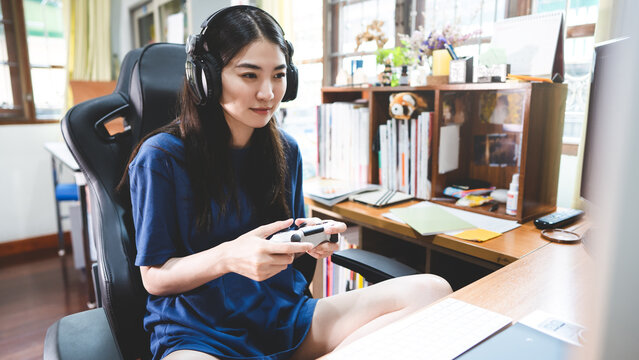 Beautiful young adult asian woman playing a console game at home on days