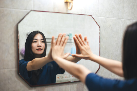 Young adult smile asian woman practice self talk conversation in the morning in bathroom at home.