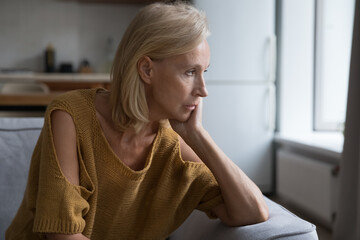Depressed mature blonde lady looking at window away with unhappy, frustrated, disappointed stare,...