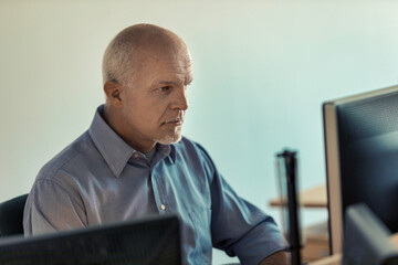 middle-aged man uses a PC workstation studies and learns - obrazy, fototapety, plakaty