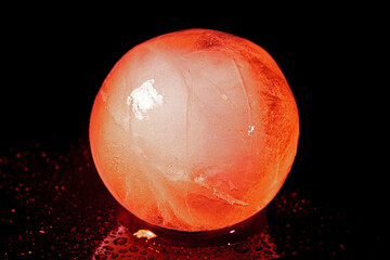 Red ice ball reflection on black background.